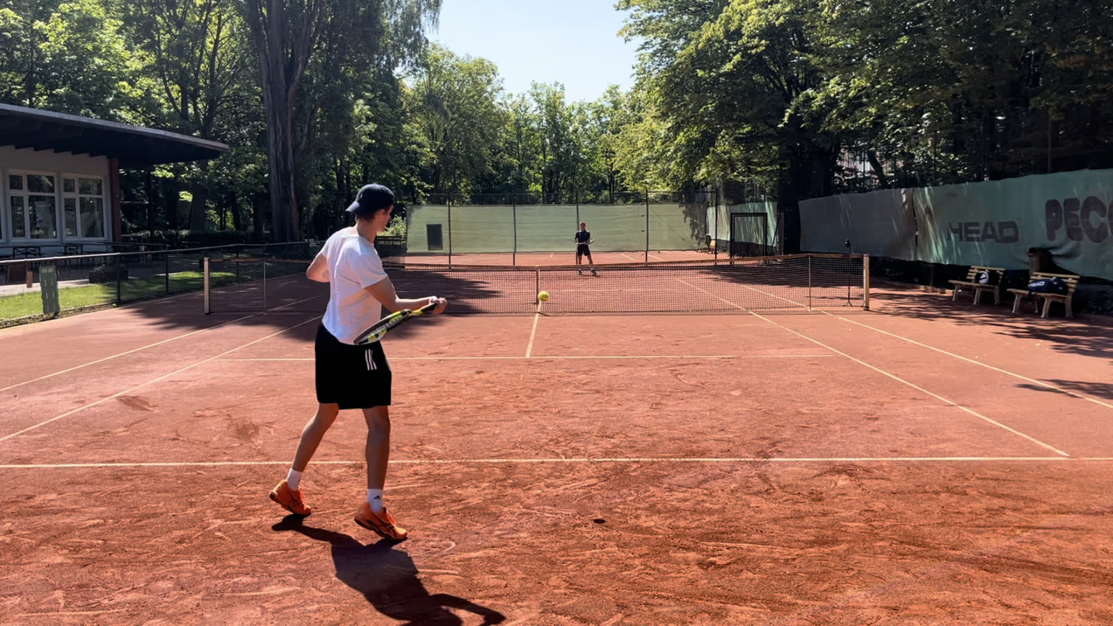 Janos Wartig beim Tennis auf dem Sandplatz, die Kamera steht hinter der Grundlinie